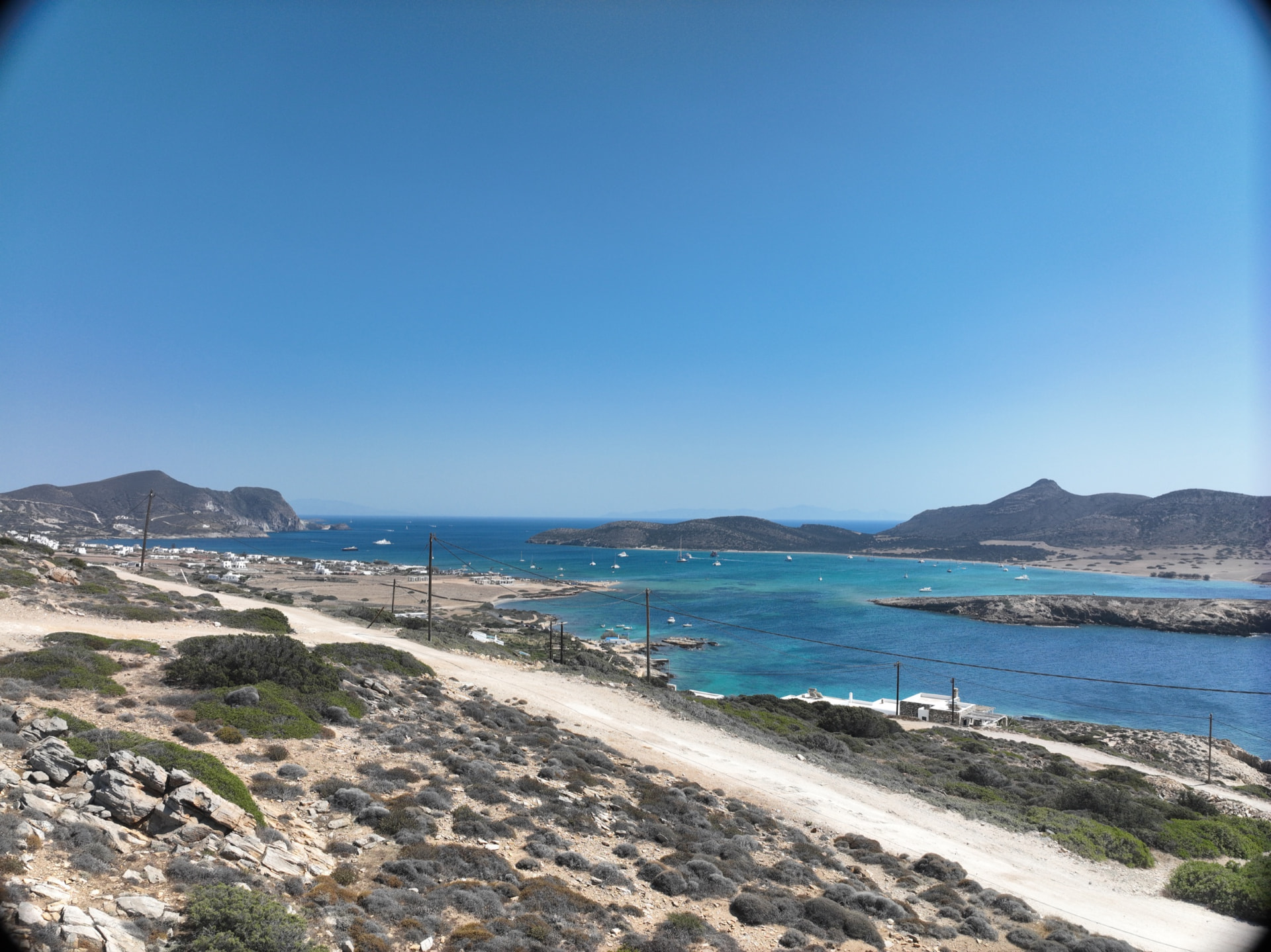 A wide view across the bay at Agios Georgios with turquoise shallows and dry hills.